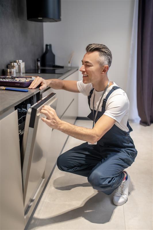 working-mood-smiling-man-peeking-into-open-door-builtin-dishwasher-modern-kitchen.